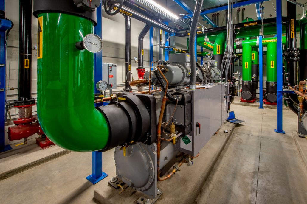 Room full of refrigeration compressors and associated controls for ice production.
